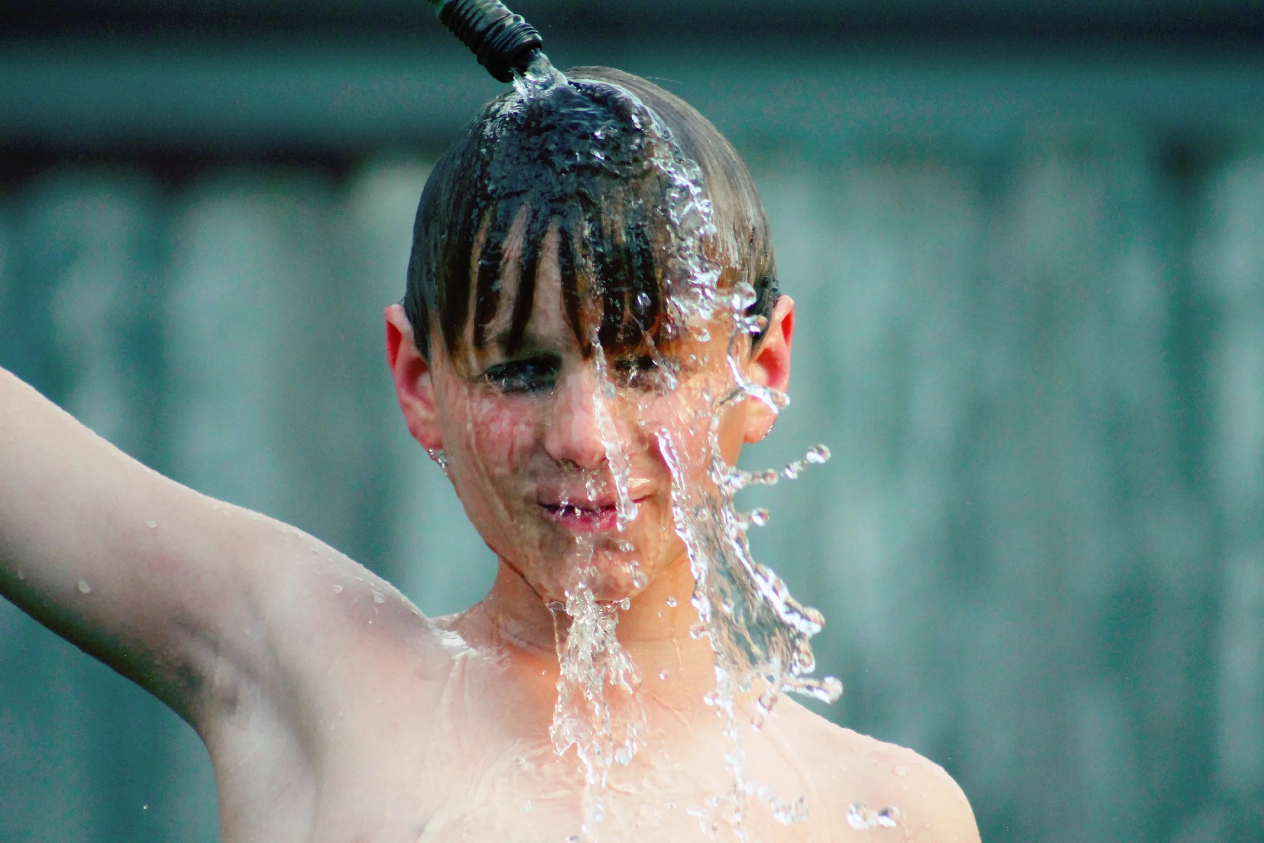 Boy spraying himself with hose