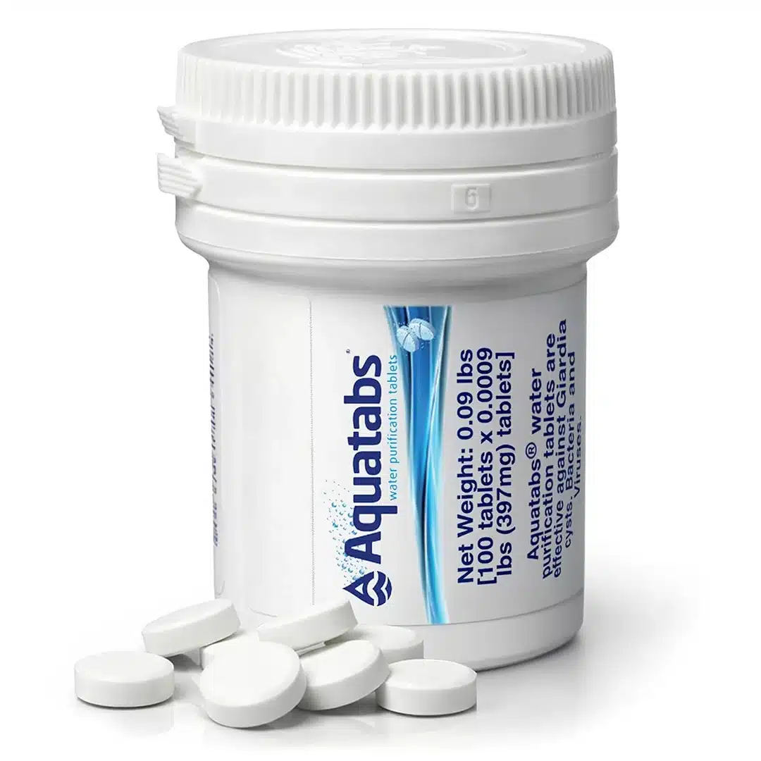 Bottle of Aquatabs water purification tablets with several white round tablets spilled in front of it.